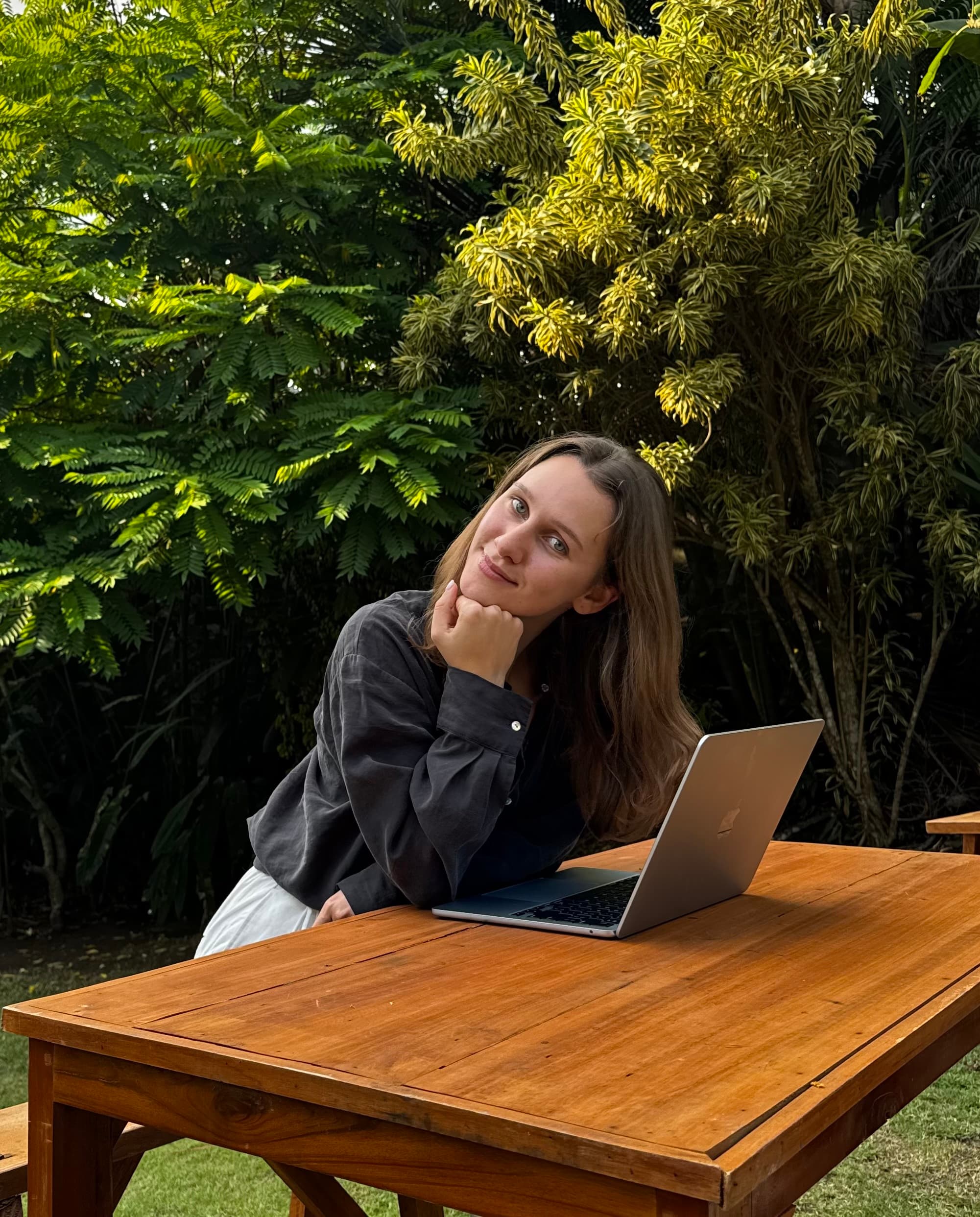 Mariia sitting with her laptop surrounded by lush greenery